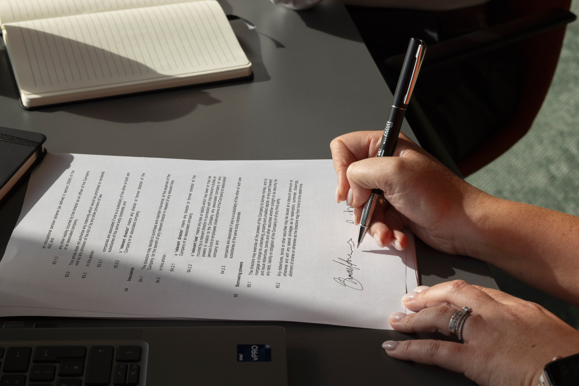 Close-up of a person signing a contract document, illustrating legal agreements, consumer protections and contractual disputes.